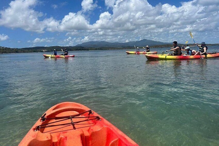 Kayakers on a calm lake with clear water and mountains in the background. 5