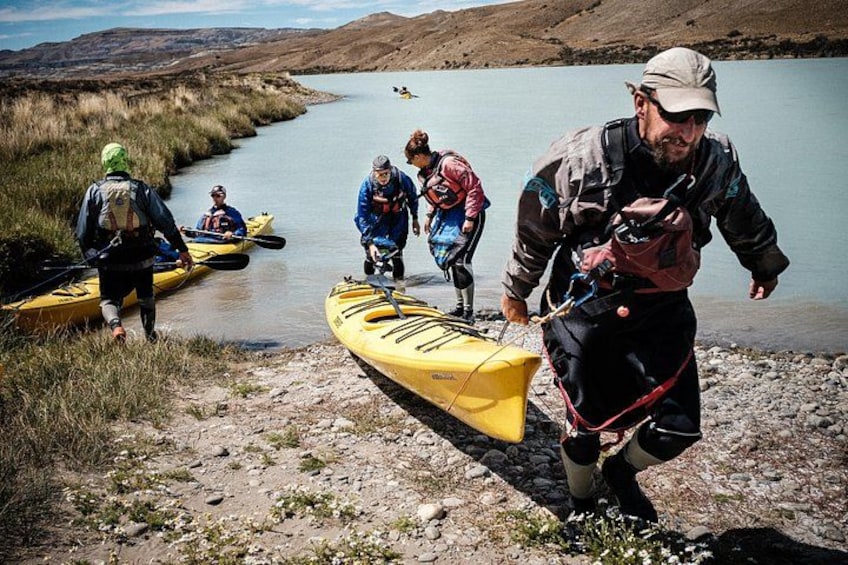 People in kayaks and a canoe near a riverbank. 5