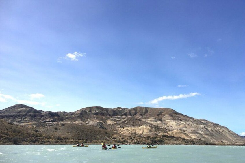 A calm lake with kayakers, a mountain in the background, and a clear sky. 4