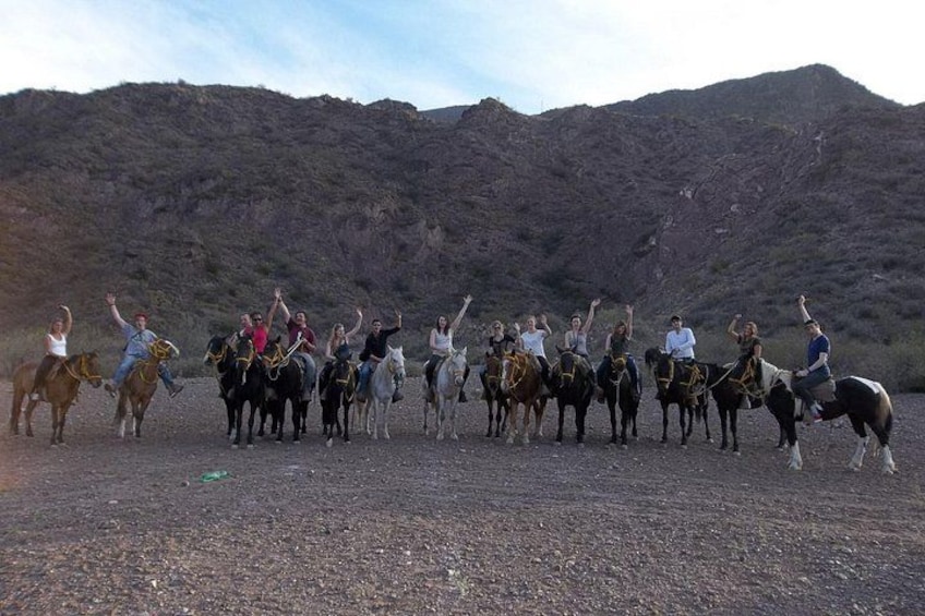 A group of people on horseback in a desert landscape with mountains in the background. 5