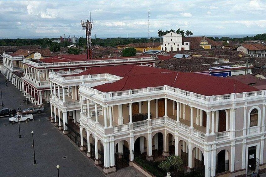 A white colonial-style building with a red roof, surrounded by other similar buildings and a clear sky. 2
