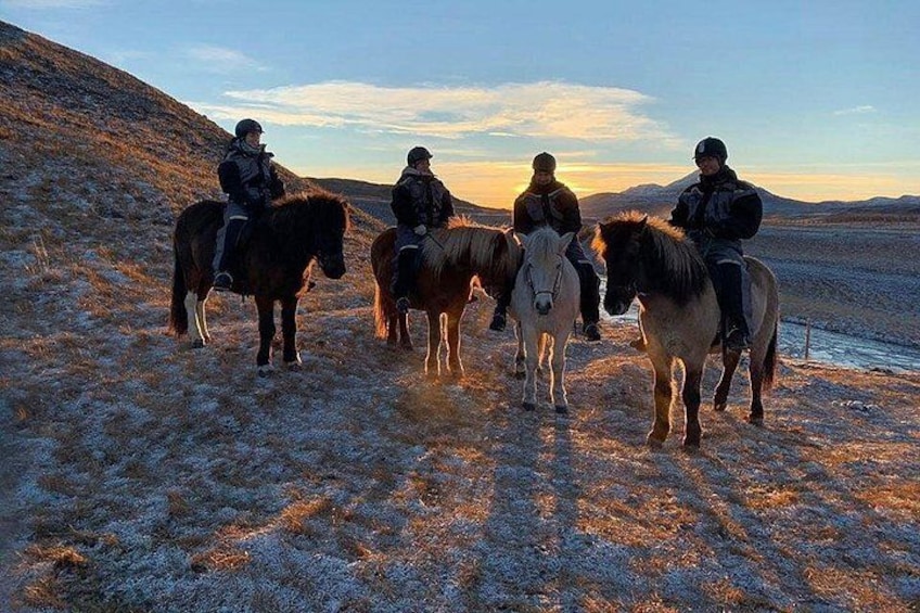 Four people riding horses on a frosty hillside. 3