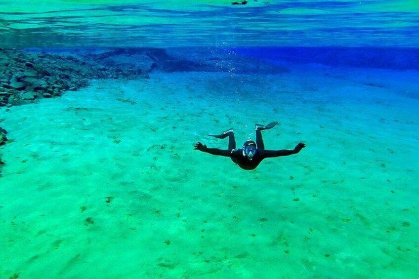 A person swimming underwater in clear turquoise water. 2