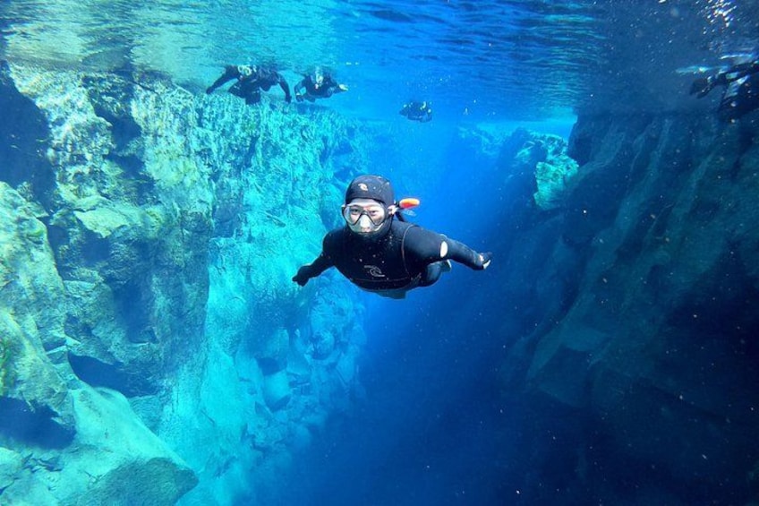 A diver swimming underwater with a rocky landscape. 5