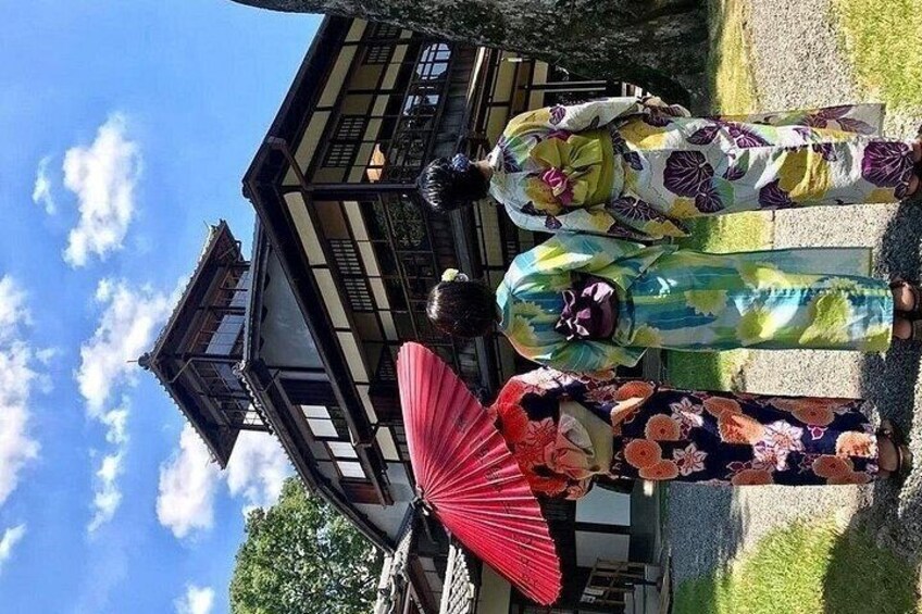 Two people in traditional Japanese attire, a building with a wooden structure, and a red umbrella. 2