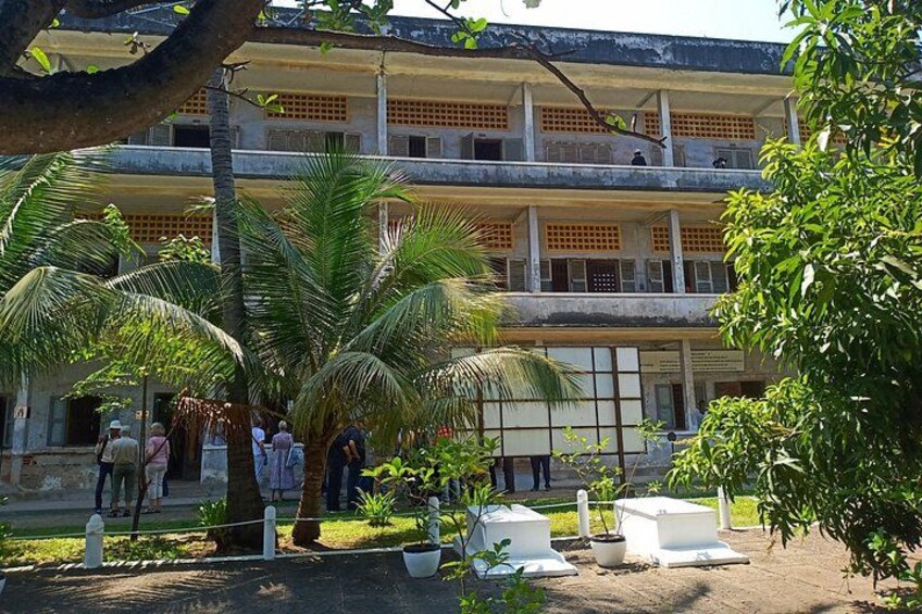Un edificio de varios pisos con un patio, palmeras y gente caminando. 2