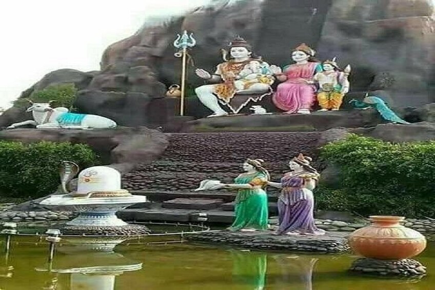 A temple with statues, a pond, and a rocky backdrop. 2