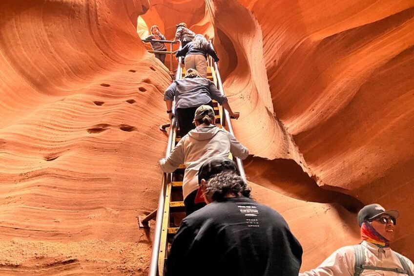 Personas escalando una escalera en un cañón estrecho con paredes de roca roja. 4