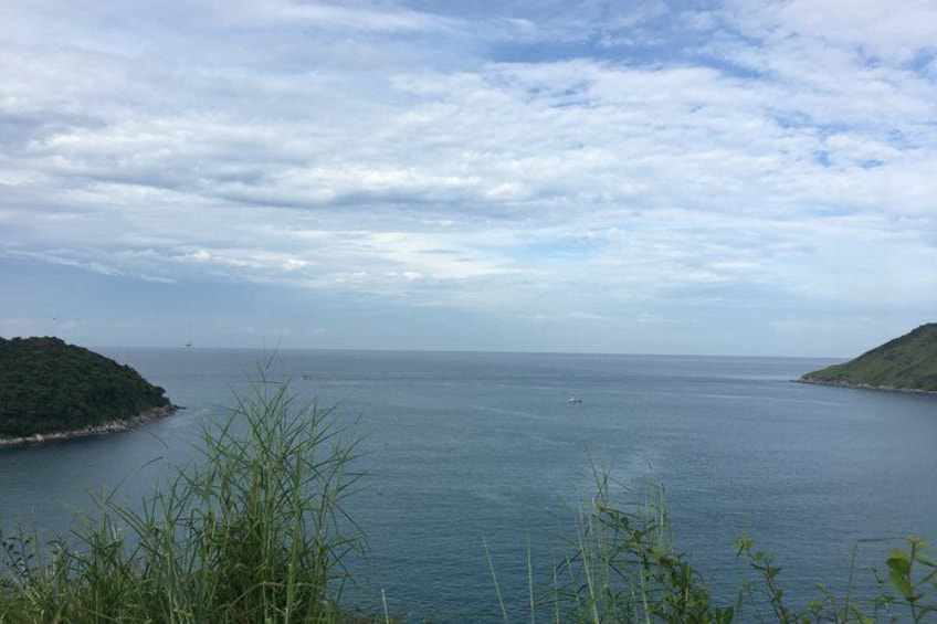 Mare calmo con una piccola barca, un'isola in lontananza e un cielo nuvoloso. 3