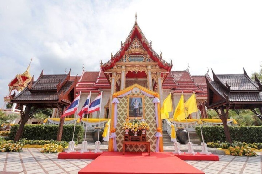 Un tradizionale tempio thailandese con un santuario centrale a tetto rosso, circondato da edifici più piccoli e bandiere. 5