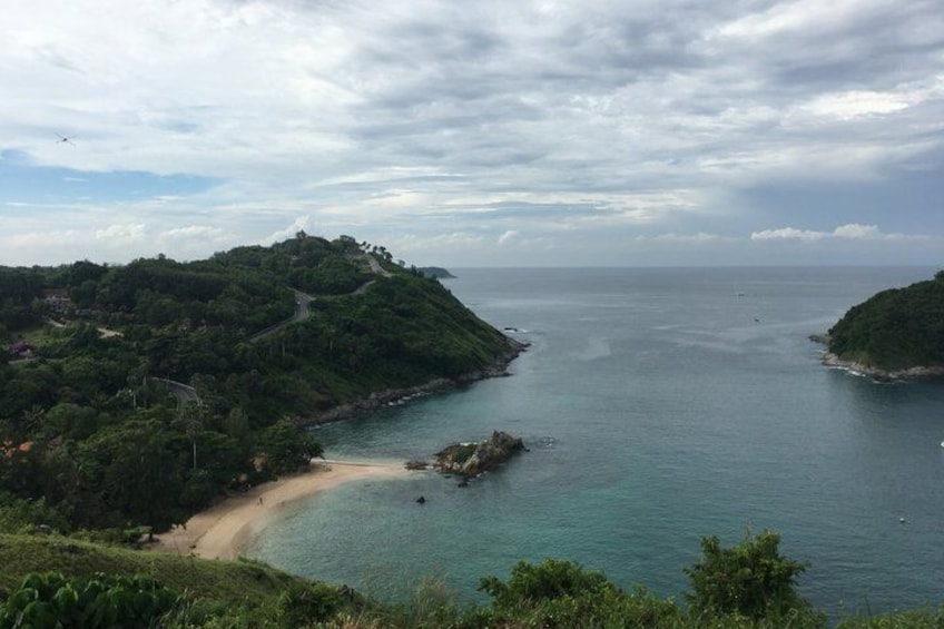 Paesaggio costiero con spiaggia, una piccola isola e un terreno collinare. 2