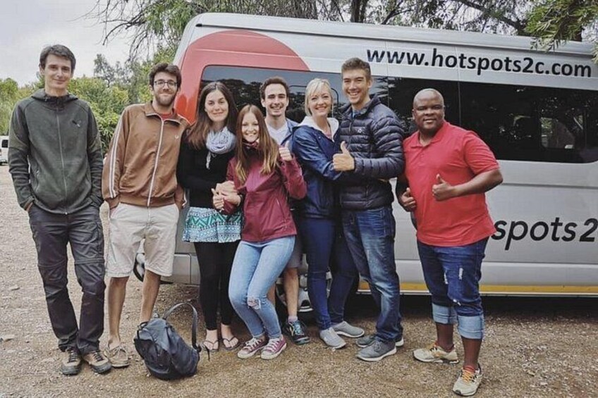 A group of people standing in front of a bus with the website 'www.hotspots2.com' visible. 2