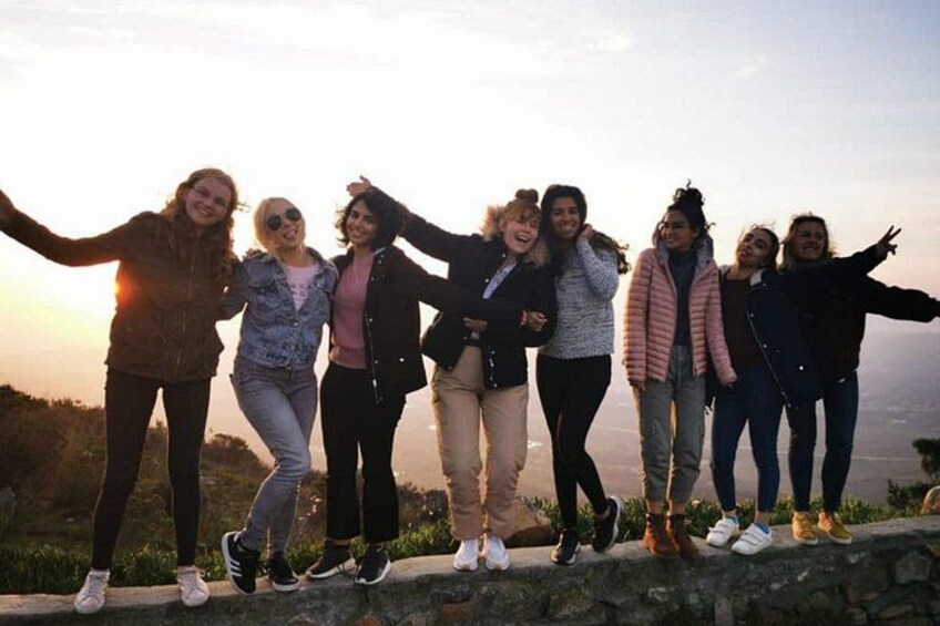 A group of people standing on a stone wall with a scenic view of the landscape. 3