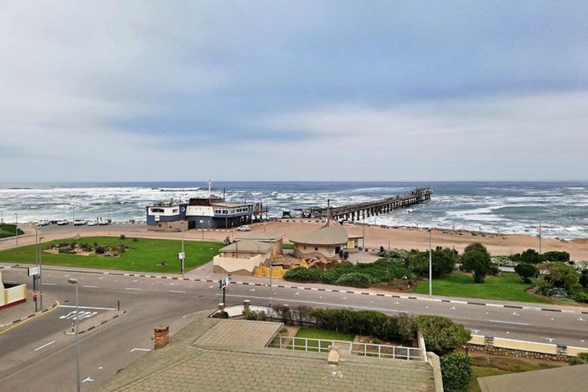 A coastal town with a pier extending into the ocean, a beach, and a road leading to a building. 3