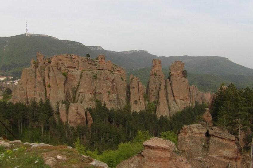 A rocky mountain landscape with prominent rock formations and a transmission tower in the distance. 5