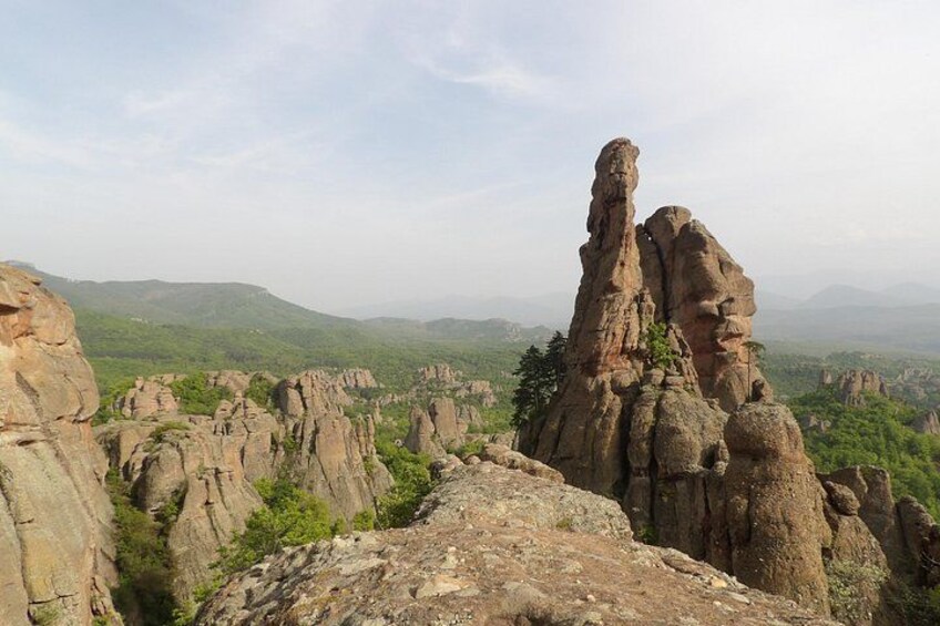 A rocky landscape with prominent rock formations and a distant view of green hills. 3