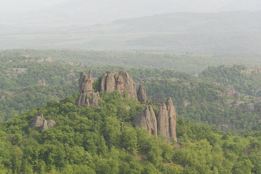 A landscape with prominent rock formations surrounded by dense green forest. 4