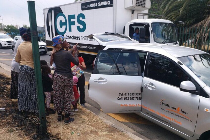 A catering service vehicle parked on the side of a road with people standing nearby. 5