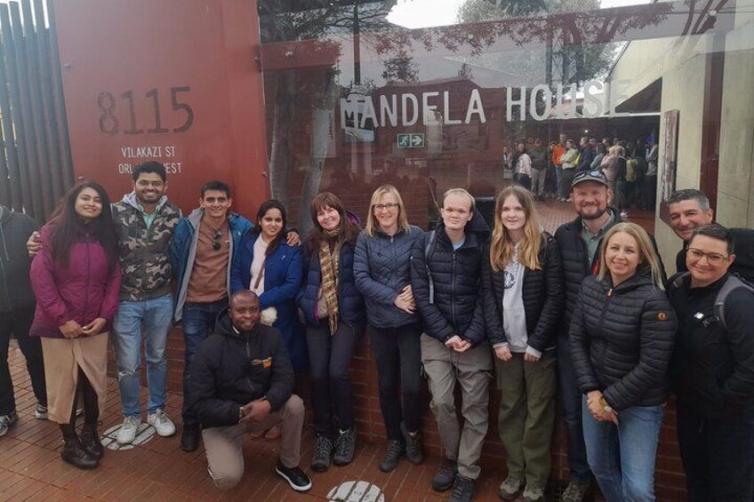 A group of people posing in front of a building with a sign that reads "Mandel Hotel". 3