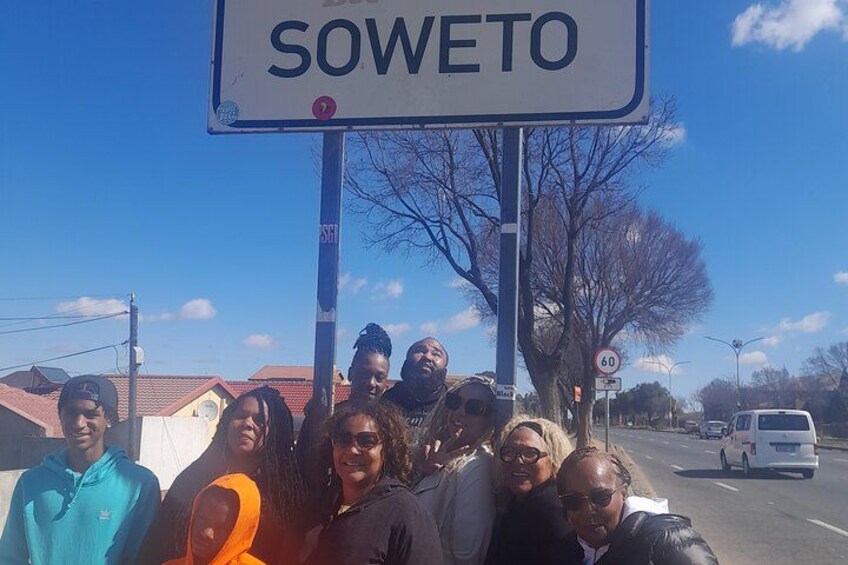 A group of people standing in front of a sign that reads "SOWETO". 2