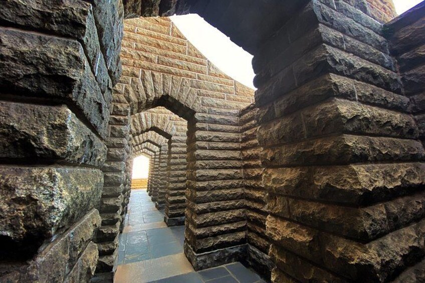 A stone corridor with arched passageways and a tiled floor. 4