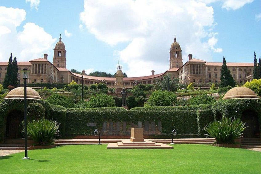 A large building with domed towers, surrounded by well-manicured gardens and hedges. 4