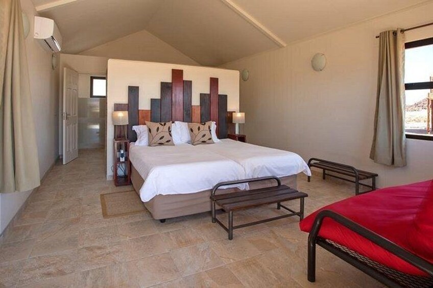 A bedroom with a large bed, bedside tables, a red chair, and a decorative wall panel. 4
