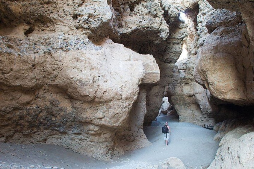 A person walking through a narrow canyon with rocky walls. 3