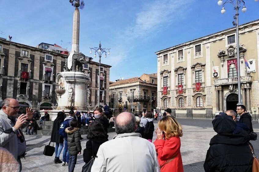A public square with a central monument, surrounded by historic buildings with flags. 2