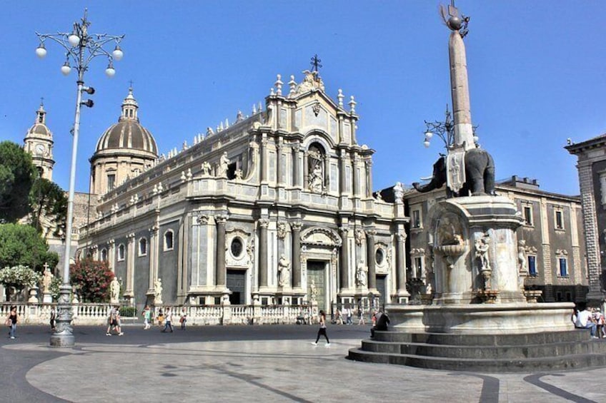 A historic cathedral with intricate architecture, a central fountain, and a statue. 4