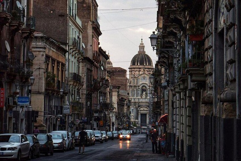 A street with parked cars, historic buildings, and a church with a dome in the background. 5