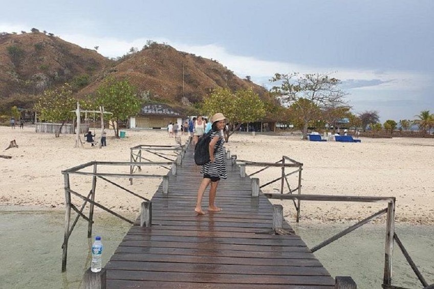 Un muelle de madera que conduce a una playa arenosa con un paisaje montañoso al fondo. 3