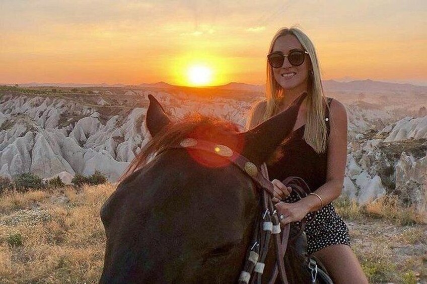 A person riding a horse in a landscape with white rock formations during sunset. 1