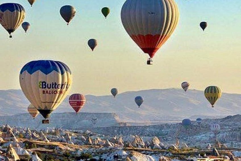 A group of hot air balloons flying over a snowy landscape with mountains in the background. 4