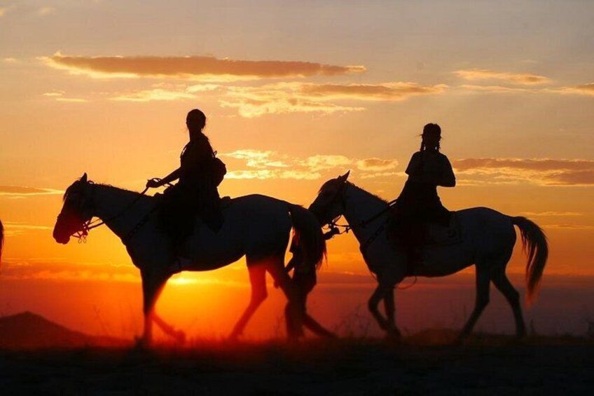 Silhouettes of three people riding horses against a sunset. 3