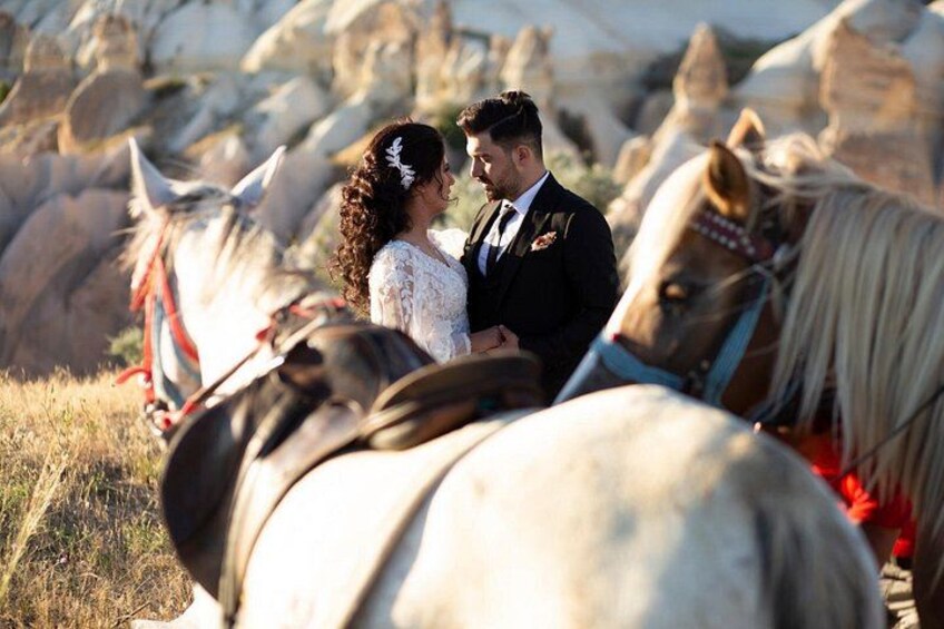 A couple embracing in a field with horses. 2