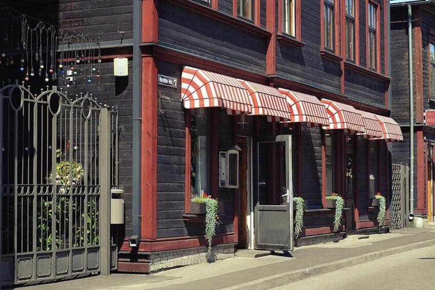 En bygning med en rødstribet markise, en sort jerngitterport og plantekasser. 5