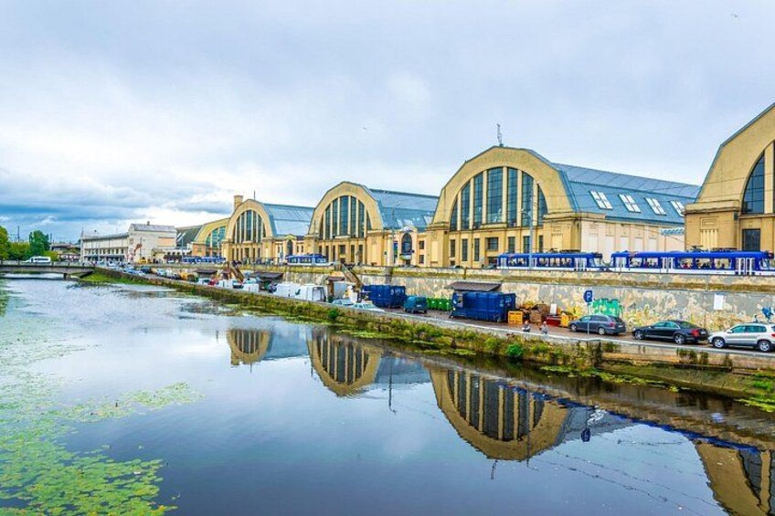 En flod der spejler en togstation med buet arkitektur og en bro. 2
