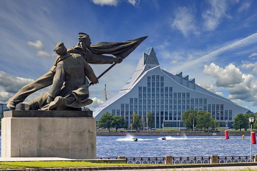 En statue af en mand med et sværd foran en moderne bygning ved en flod. 4