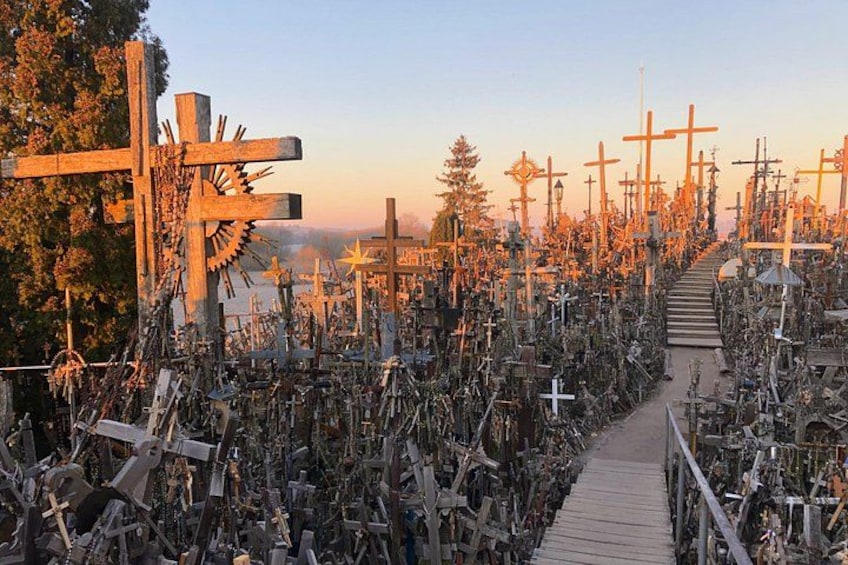 A cemetery with numerous crosses and a wooden walkway. 1