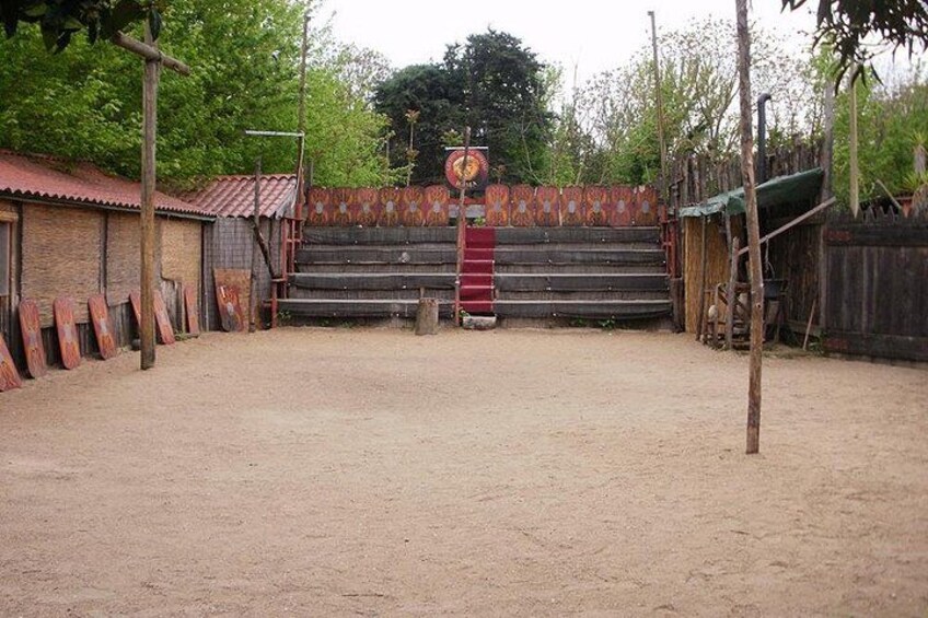 Un terrain en terre battue, une clôture en bois, un portail en métal et un bâtiment avec un toit rouge. 2