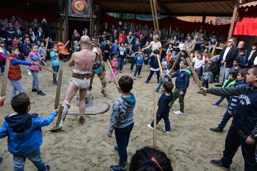 A group of children playing in a sandy area with adults in the background. 4