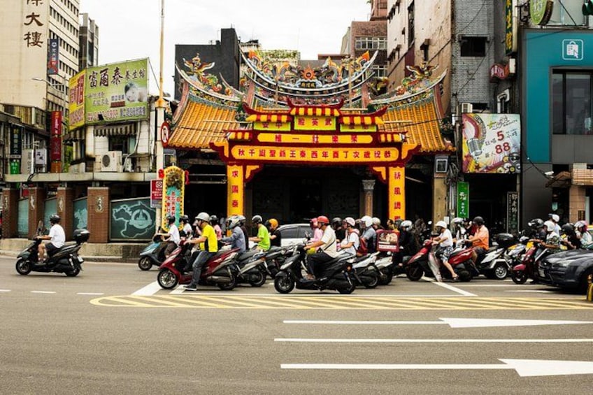 Una calle con una puerta china tradicional, motocicletas alineadas y edificios con letreros. 1