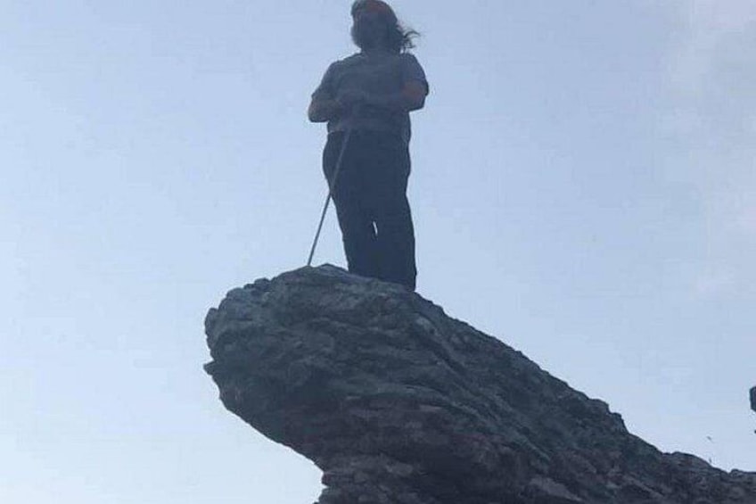 A person standing on a rock formation with a walking stick. 3