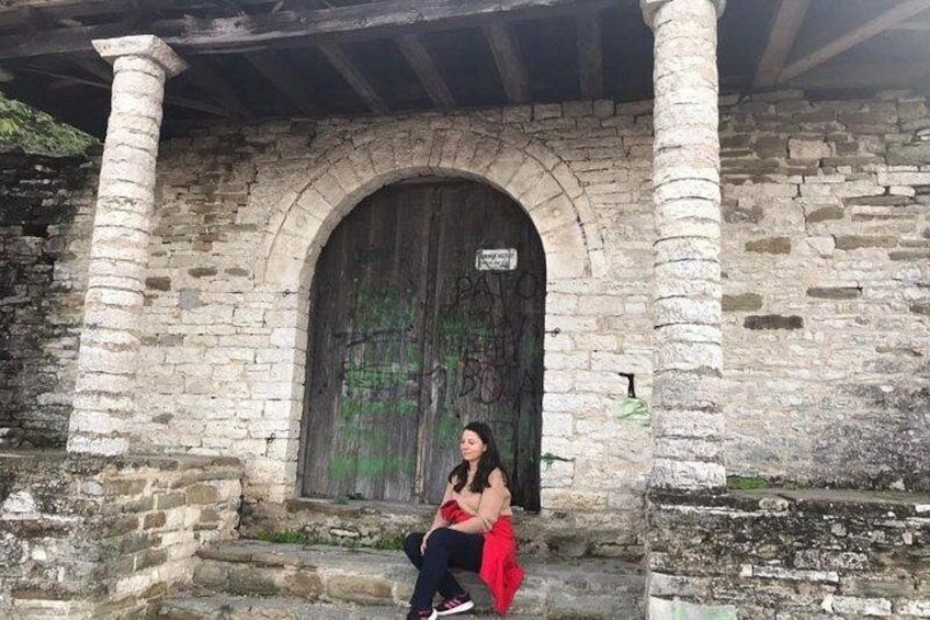 A woman sitting on steps in front of a stone building with a large arched doorway. 5