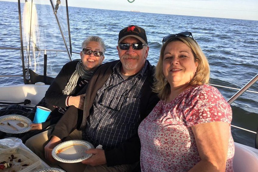 Three people on a sailboat with a view of the ocean. 4