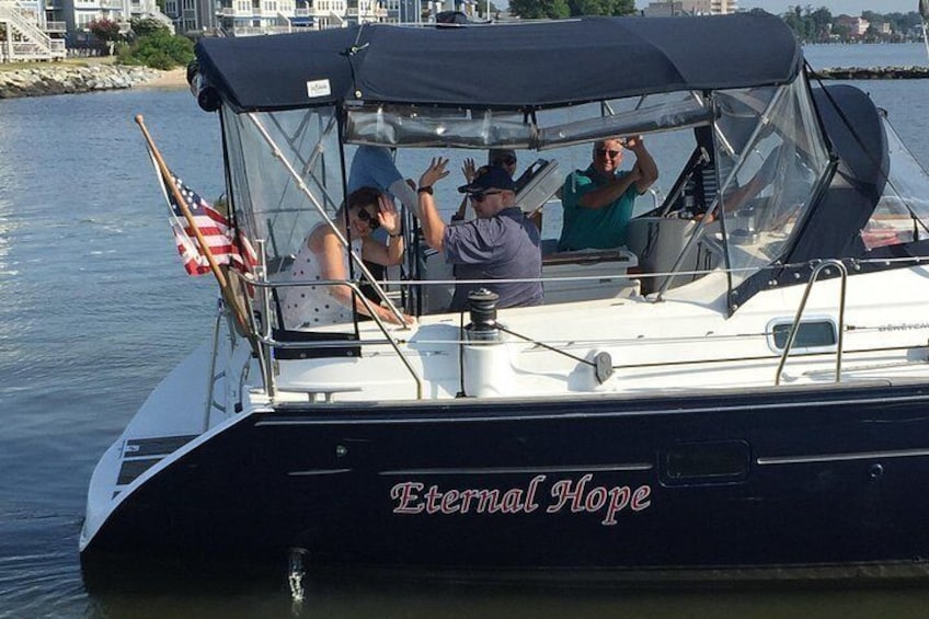 En båd ved navn 'Eternal Hope' med folk ombord, et amerikansk flag og en havnefront i baggrunden. 3