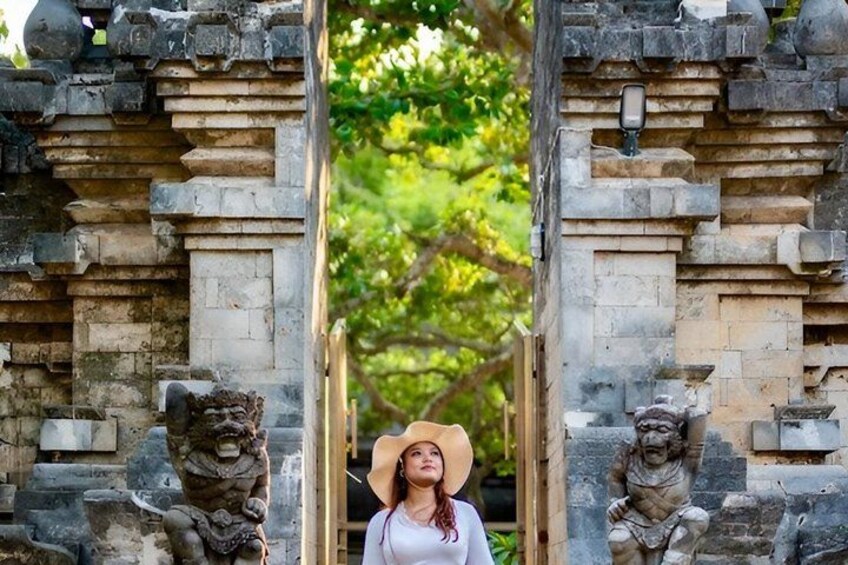 A stone gateway with two lion statues, a person wearing a hat, and a pathway leading through the archway. 4
