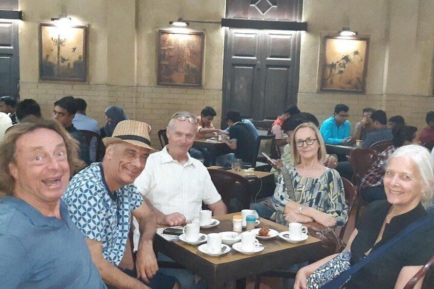 Un groupe de personnes est assis à une table dans un restaurant, avec d’autres clients en arrière-plan. 4