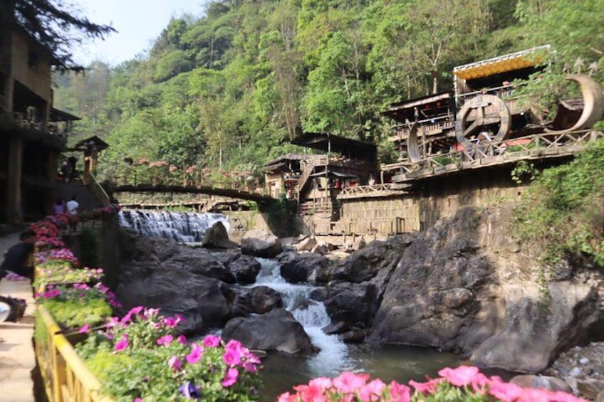 Una cascata, un ponte di legno e un edificio dall'architettura tradizionale. 2